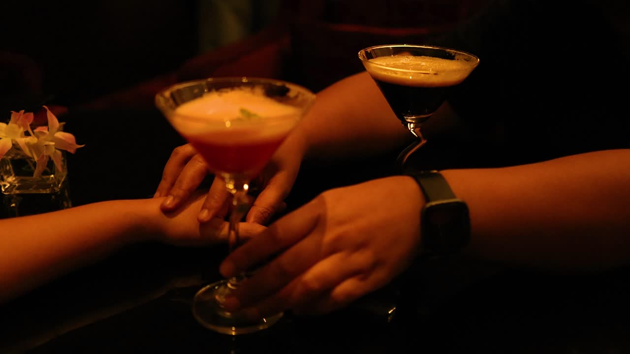 due persone che fanno scattare i bicchieri in un bar scarsamente illuminato