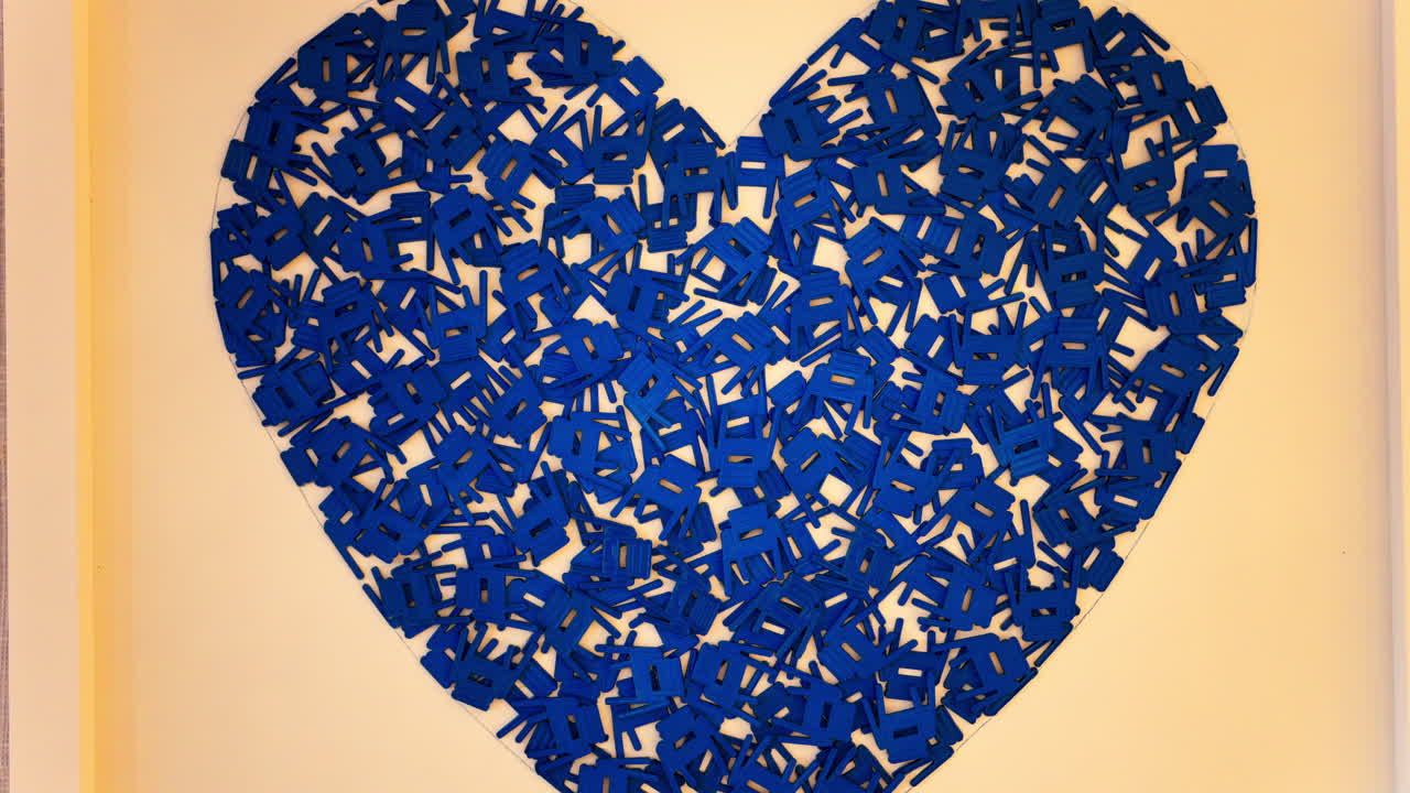 Nice, France - March 17, 2025: Heart made out of small blue chair figurines on a yellow wall