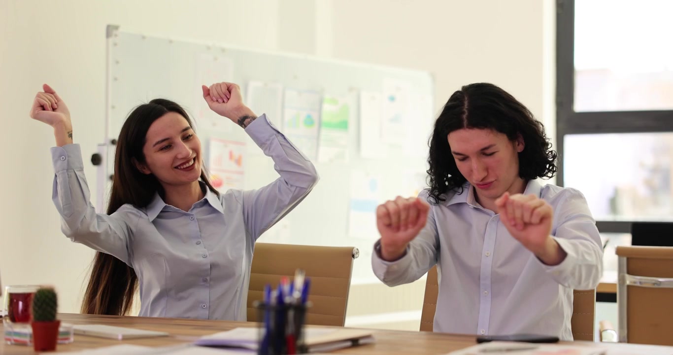 Homem e mulher celebram triunfo com gestos expressivos na mesa