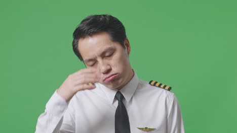 close up of asian man pilot having a headache while standing in the green screen background studio