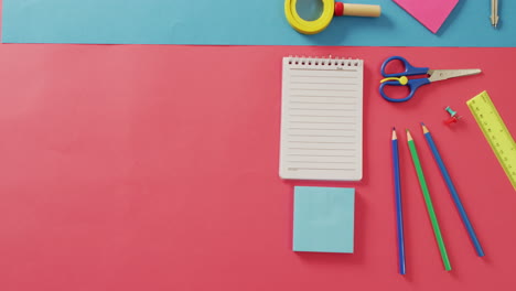 video of notebook with copy space and school items on pink and blue background