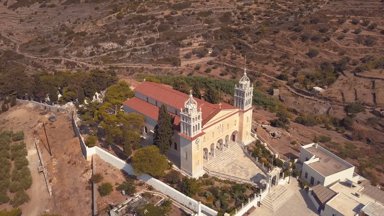 Ripresa aerea con drone che inizia dal fianco di una chiesa e gira lentamente per rivelare la facciata di una bellissima chiesa sull'isola di Lefkes, Grecia