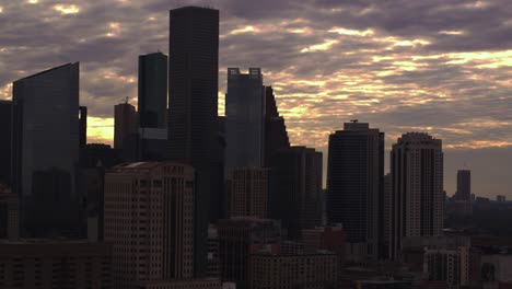 Drone-dolly-shot-moving-forward-away-from-downtown-Houston,-Texas-during-sunset