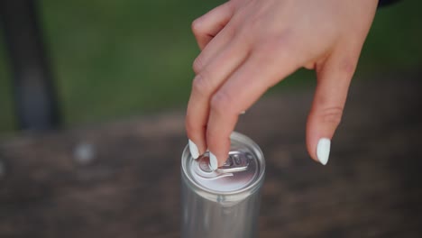 mano femenina con uñas de manicura golpea los dedos contra la lata de bebidas de aluminio