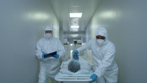 hospital workers in protective suits pushing patient on gurney