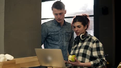 pareja de dos personas elegantes, un chico y una chica, en trajes urbanos modernos navegando por la web en un espacio interior bien iluminado