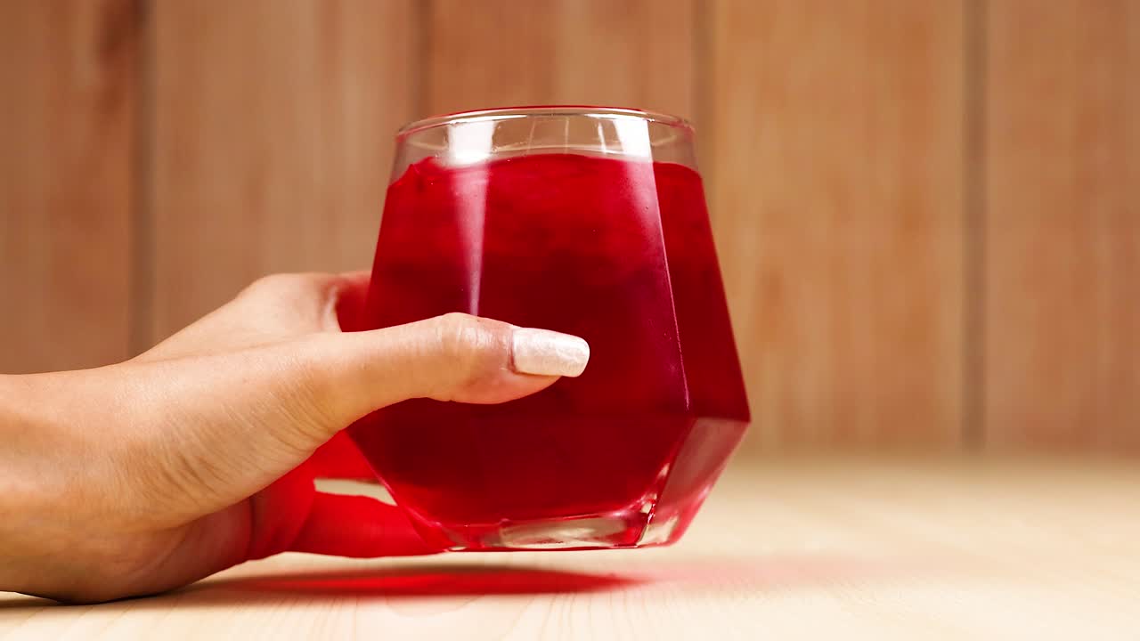 A hand reaches for a red beverage