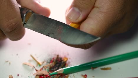 Footage-of-hands-slowly-sharpening-a-pencil-and-some-coloured-pencils-with-a-sharp-knife