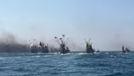 인도네시아 자바 주 카르 (banyuwangi) 의 파티 라우트 축제 기간 동안 인도양에서 시 보트가 연기 배기가스로 여 있습니다.