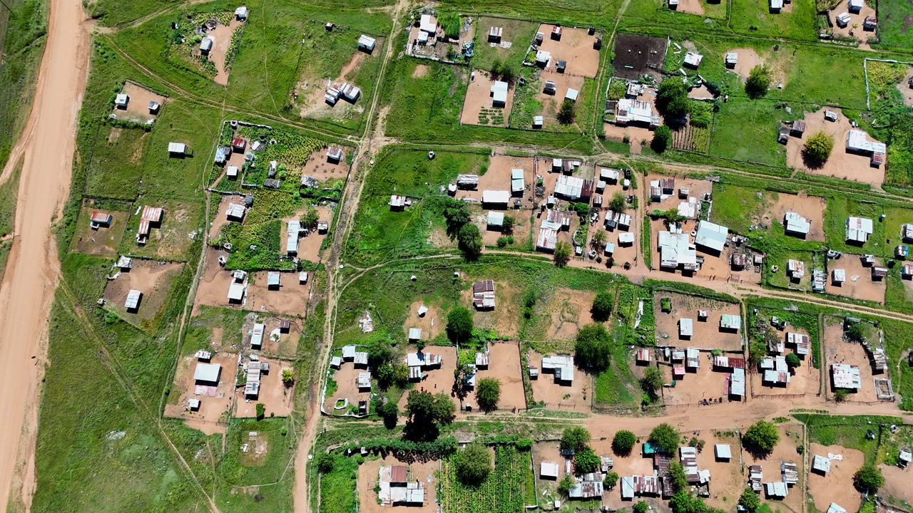 Top-down aerial view over informal settlement built next to dirt road in Africa