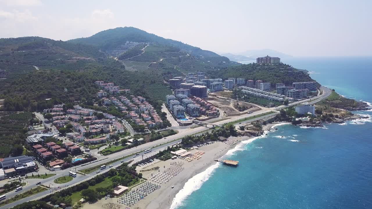 Aerial view of a coastal resort town with mountains, beach and turquoise sea