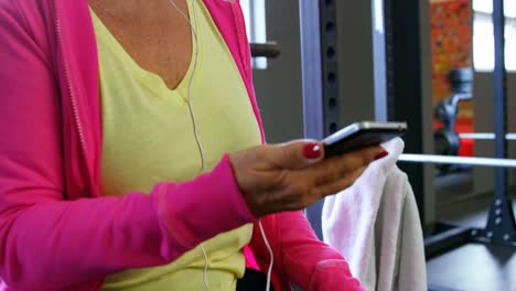 Senior-woman-listening-music-on-mobile-phone-in-fitness-studio-4k