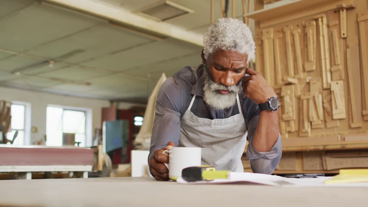 Thoughtful african american male carpenter sketching a project in a carpentry shop