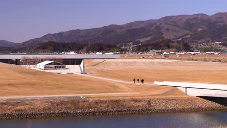 slow pan over group of tourists walking grounds of iwate tsunami memorial museum