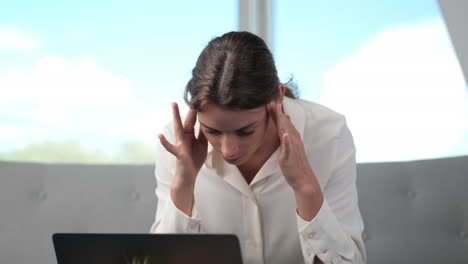 Young-woman-suffers-from-severe-headaches-and-exhaustion-at-laptop-screen-while-working-in-home-office,-close-up