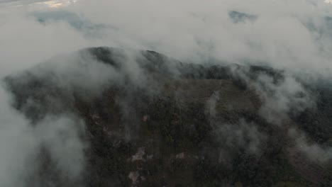 drone aerial flying through clouds, lush rainforest mountain