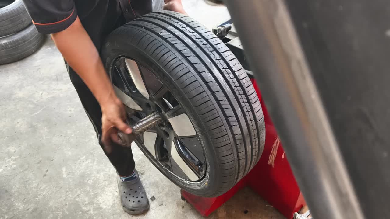 Mechanic Removing Car Wheel from Balancing Machine in Auto Shop