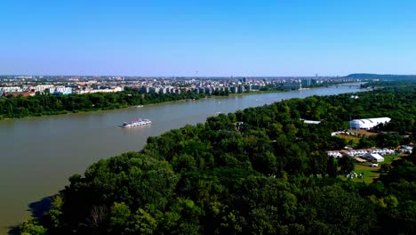 Ship-Cruising-Tranquil-River-In-Obuda-Island,-Budapest,-Hungary---aerial-shot
