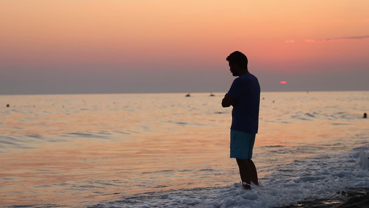 Giovane uomo al tramonto in spiaggia