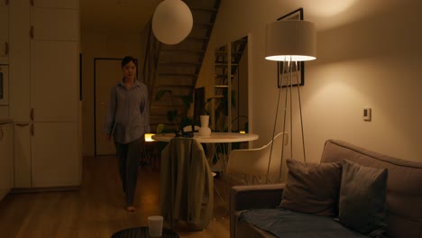 woman walking and sitting in a cozy living room at night