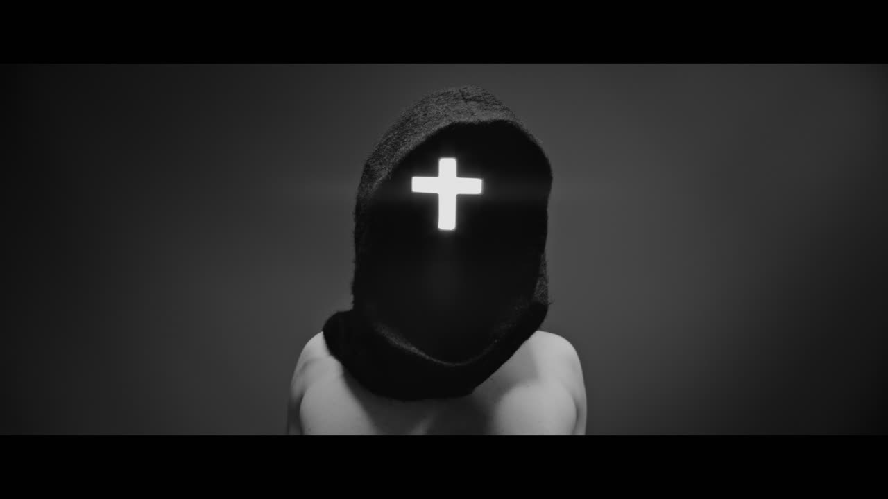 Masked and hooded man with cross of light glowing on his face rise his arms