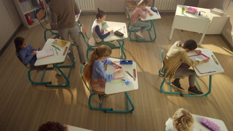 students writing in exercise books. schoolteacher looking children doing test