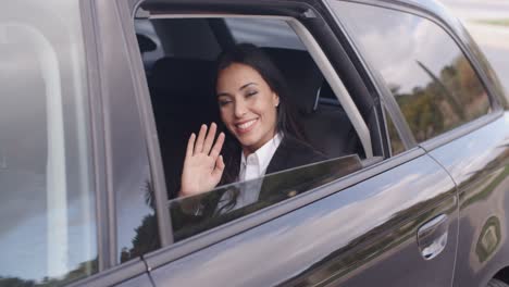 mujer de negocios linda sentada en el coche agitando la mano