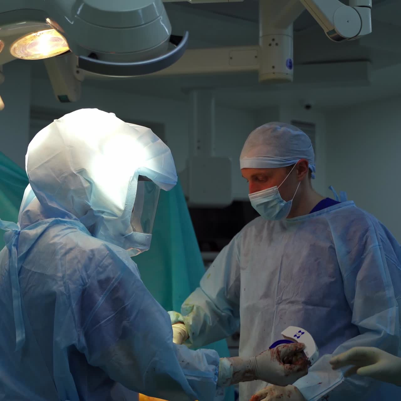 Group of surgeons in the operating room. Doctors in medical protective uniform performing operation in modern surgery room.