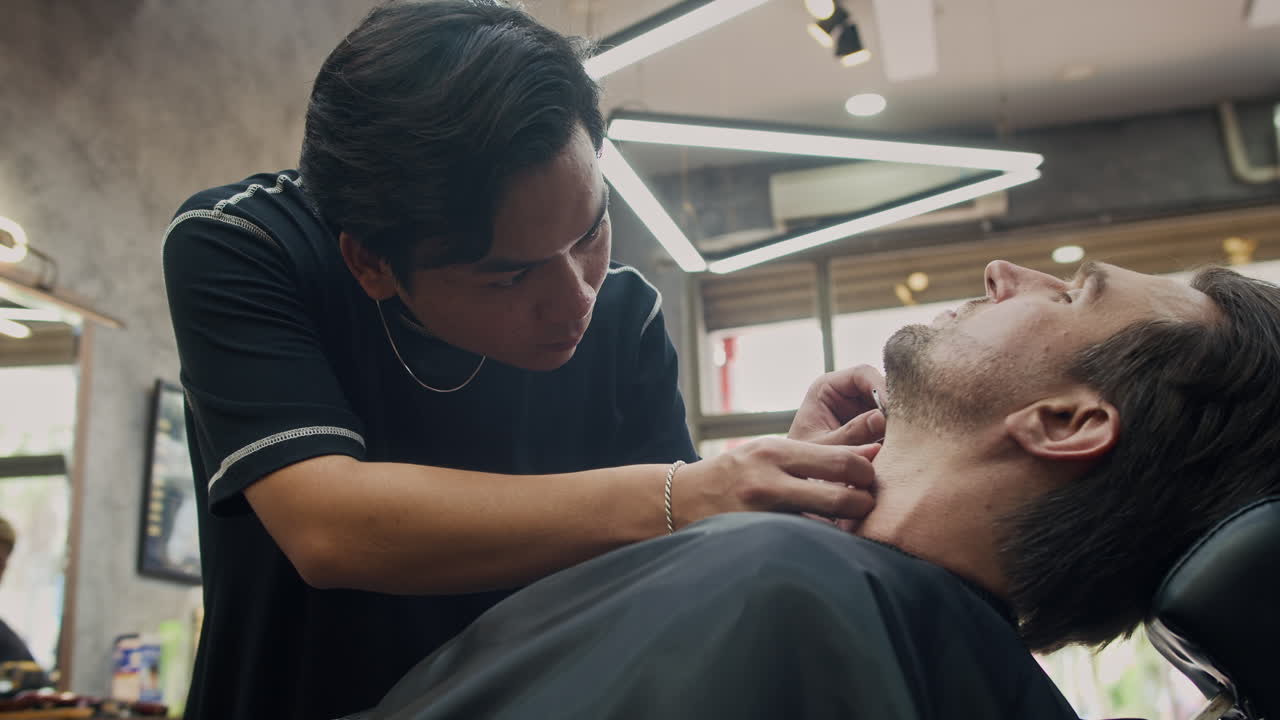 En barber, der giver en kunde en tæt barbering i en barbersalon