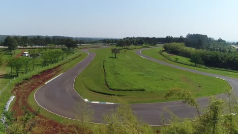 Drone-emerging-from-behind-bamboo-and-revealing-the-giant-racetrack-of-the-city-of-Oberá-in-Misiones,-Argentina