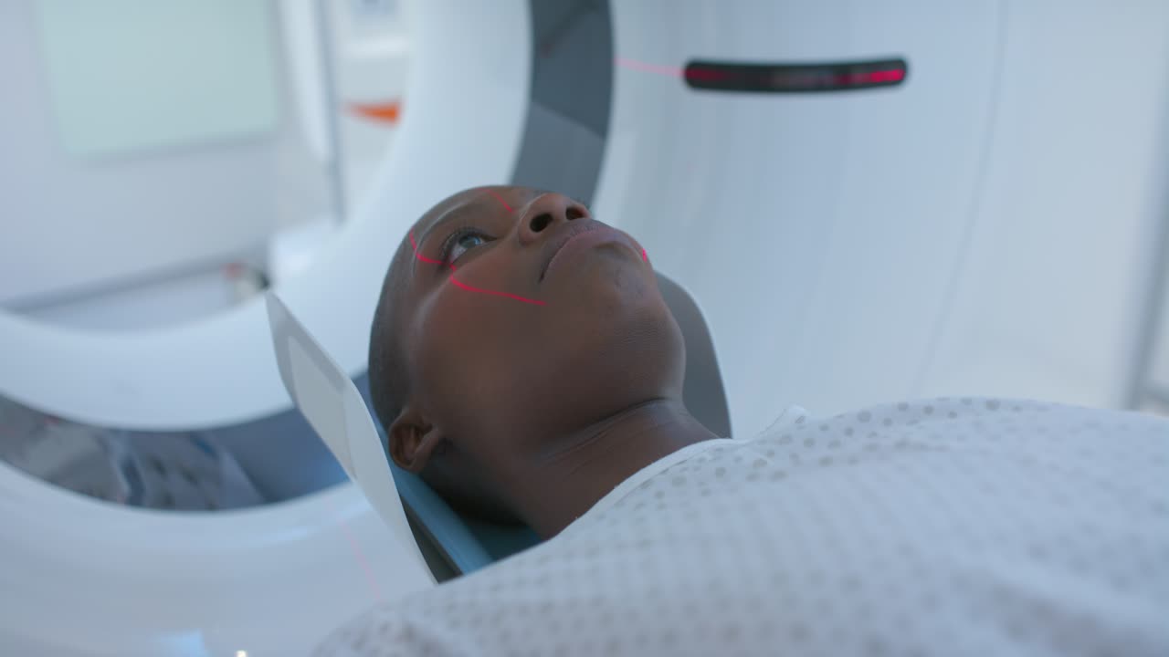 Lo scanner si sta attivando e proietta linee laser rosse sul viso mentre allinea la scansione della testa sul lettino.