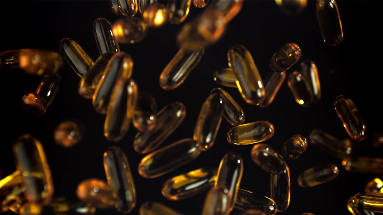 Capsule softgel di Omega 3 dorate che cadono al rallentatore