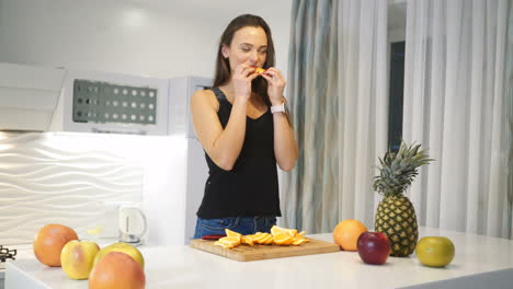 sports woman eating an orange in the kitchen. healthy eating. fresh fruits. lifestyle. fruit for breakfast.