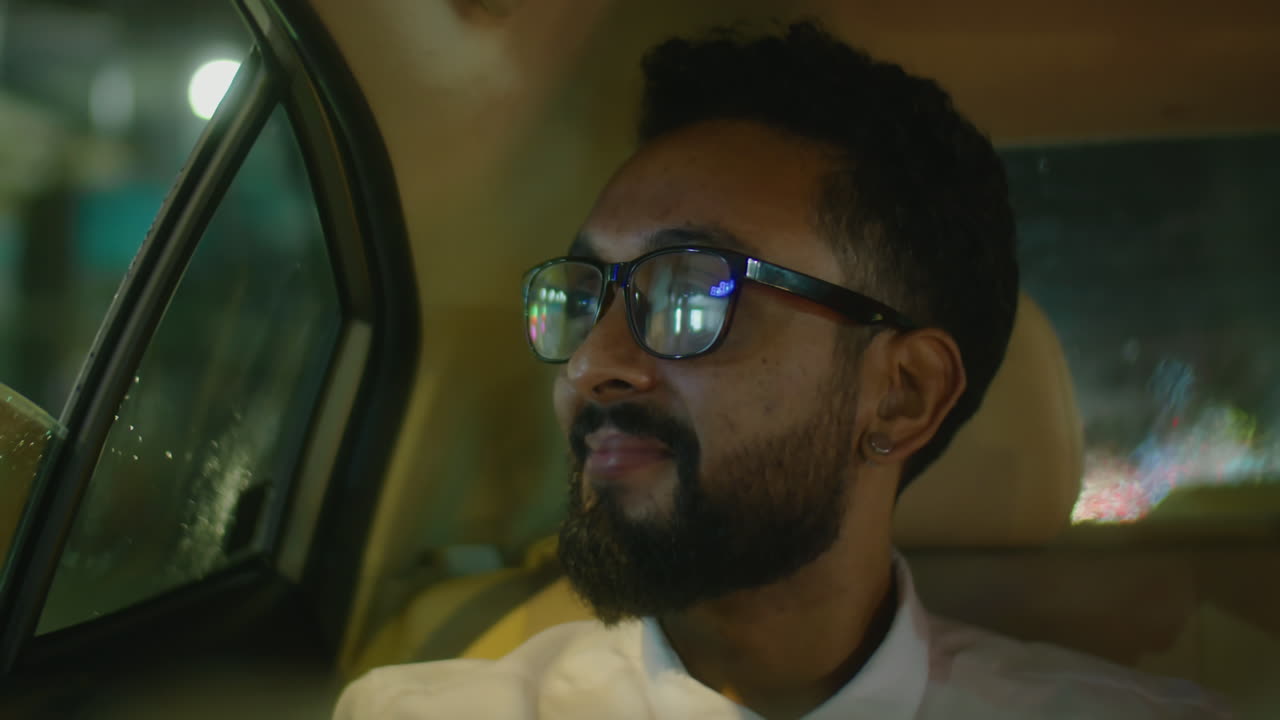 Businessman Riding in Taxi at Night and Smiling