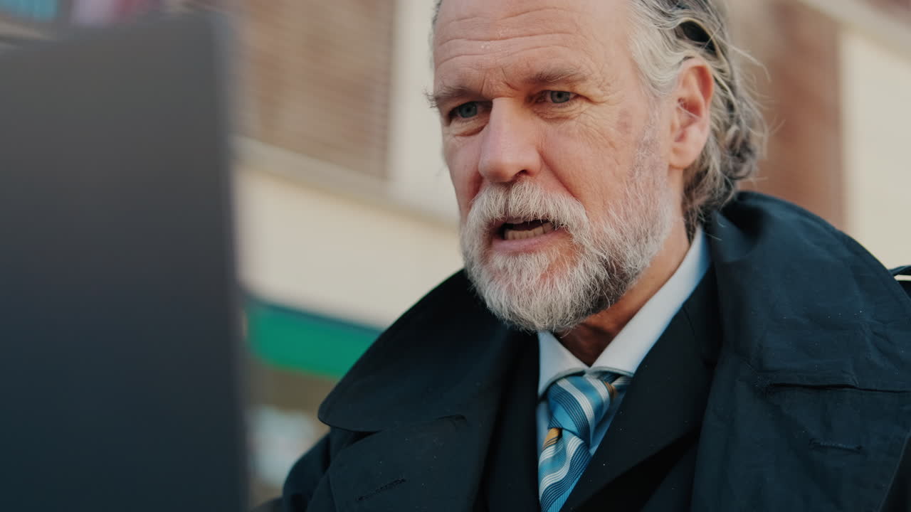 Smiling Senior Businessman Working on Laptop Outdoors