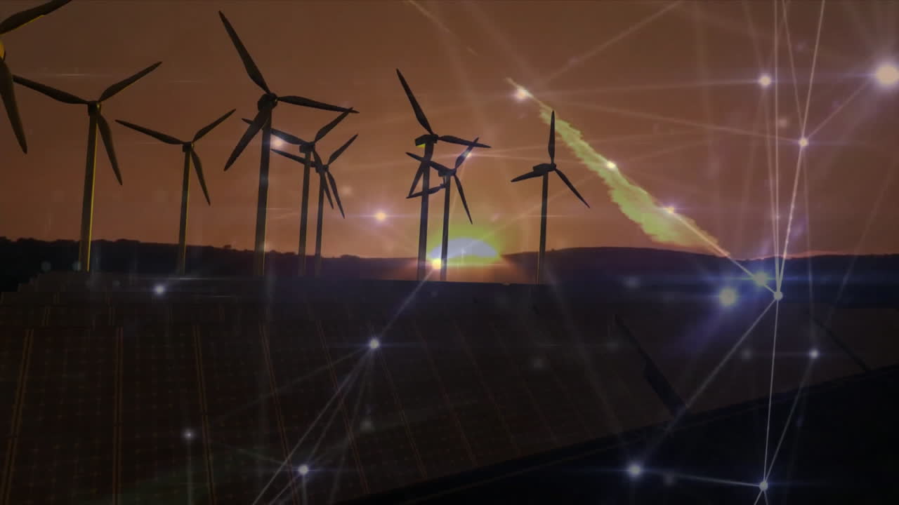 Wind turbines rising above solar panels glowing network nodes connecting orange sunset sky