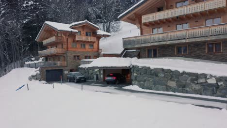 Drone-Siguiendo-El-Coche-De-Conducción-Que-Estaciona-En-El-Garaje-De-Un-Lujoso-Chalet-En-Un-Paisaje-Cubierto-De-Nieve