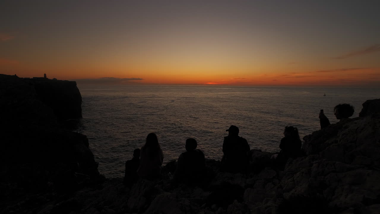 수평선에서 아름다운 바다 풍경과 화려한 일몰을 즐기는 사람들의 실루엣을 보여주는 뒷모습
