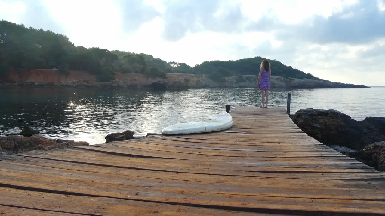 아침에 이비자 해안의 아름다움을 바라보며 활주로에 서있는 소녀