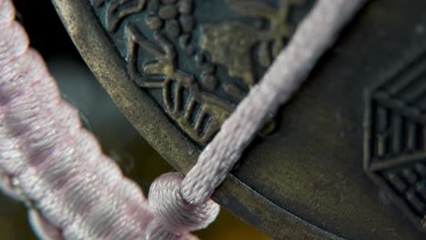 una foto macro de ensueño de una moneda de la suerte tradicional china antigua, decoración asiática de año nuevo, fondo borroso dorado brillante, agujero cuadrado, cuerdas rojas, festividad cultural, inclinación suave hasta video 4k