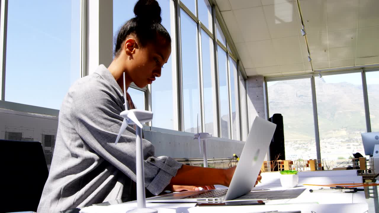 Side view of African American Businesswoman using laptop at desk in a modern office 4k
