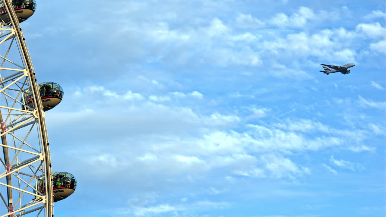 View of the rotating London Eye and flying plane in city downtown, United Kingdom. Slow motion