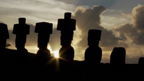 o sol espreita por trás de uma estátua da ilha de páscoa