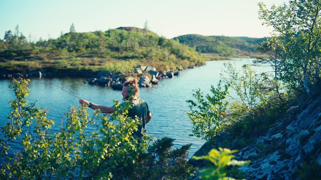 Norwegian Guy With Fishing Rod Catching Fish On A Calm Lake