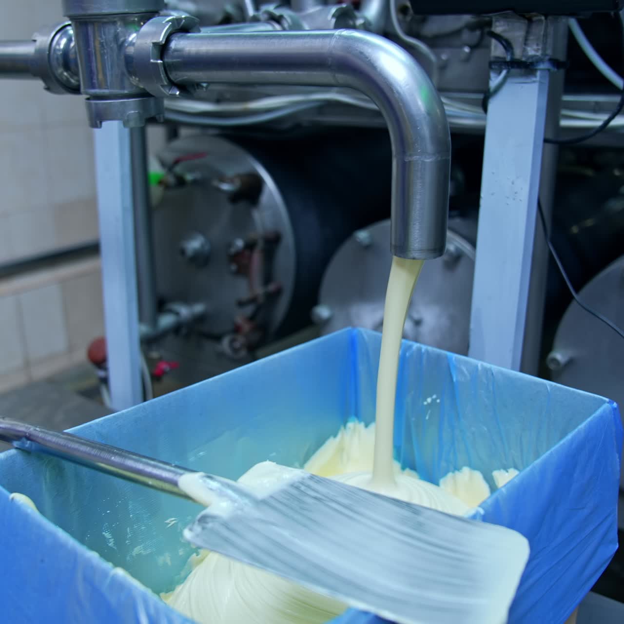 Industrial equipment for milk production. Fresh milk product pouring into special containers. Making butter on a milk factory