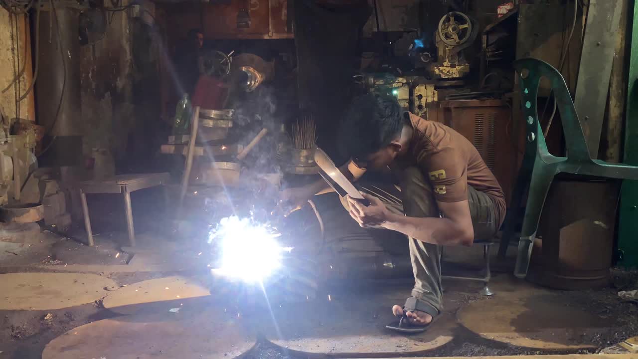 Teenage welder welding at a factory workshop in Dhaka, Bangladesh
