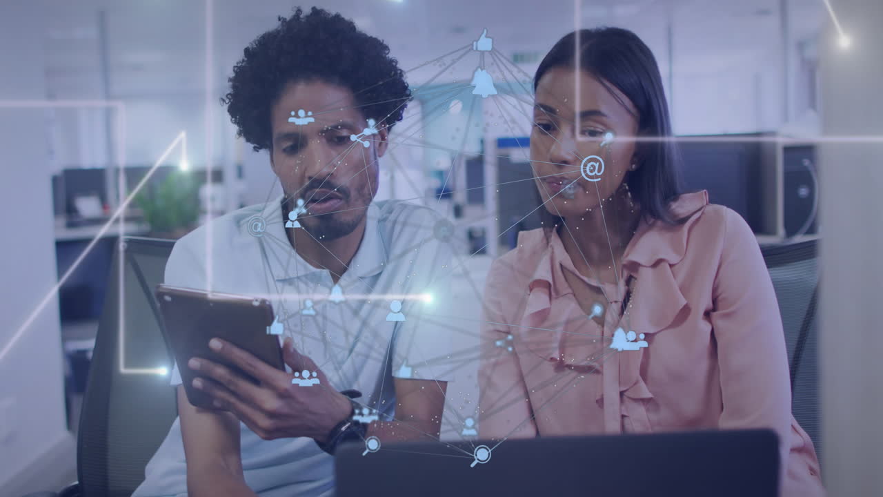 Animation of connected icons forming globe oved diverse coworkers discussing reports on laptop