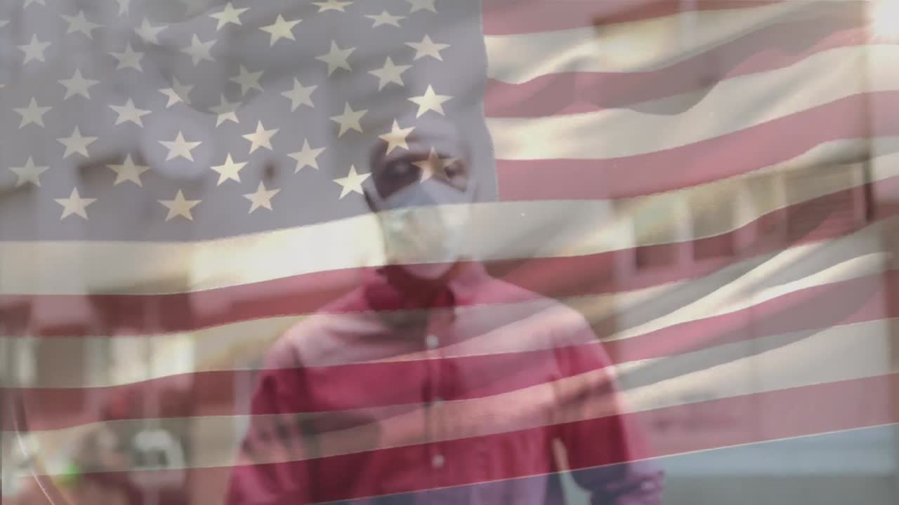 animación de la bandera de los estados unidos ondeando sobre un hombre afroamericano con máscara facial en la calle de la ciudad