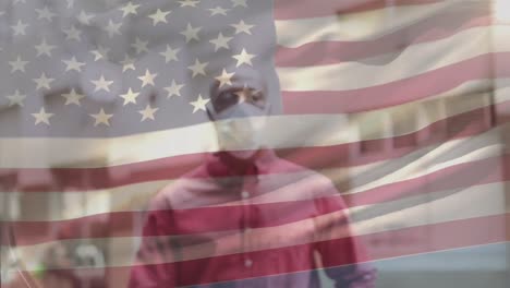 Animation-of-flag-of-usa-waving-over-african-american-man-wearing-face-mask-in-city-street