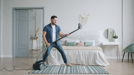 man vacuuming in a bedroom with joy